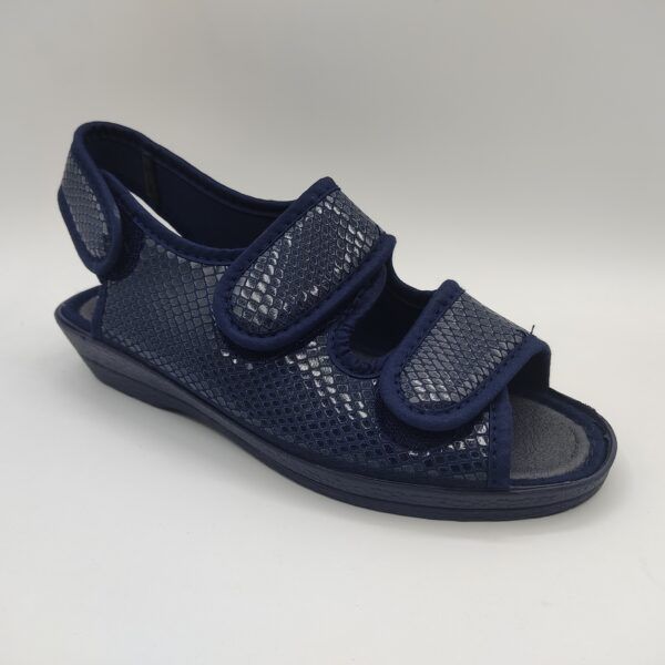 Zapatillas para personas mayores de la marca Sevillas, modelo 405496 Lycra Espejo Azul. Suela de goma en color marino con cuña de 3 cm de altura. Plantilla acolchada en color marino. Fabricadas en textil color marino con textura de escamas brillantes. Dedos y talón al descubierto. Dos velcros sobre dedos e empeine y un tercero en el talón.