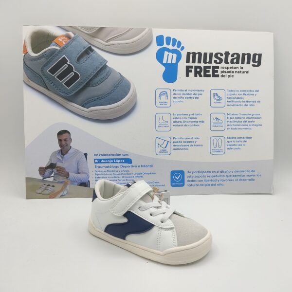Zapatillas deportivas respetuosas para niños de la marca Mtng, modelo 49304 en color blanco con detalles laterales y en el talón en color marino. Suela blanca cosida. Parte delantera en serraje gris. Cierre con cordón elástico y velcro.