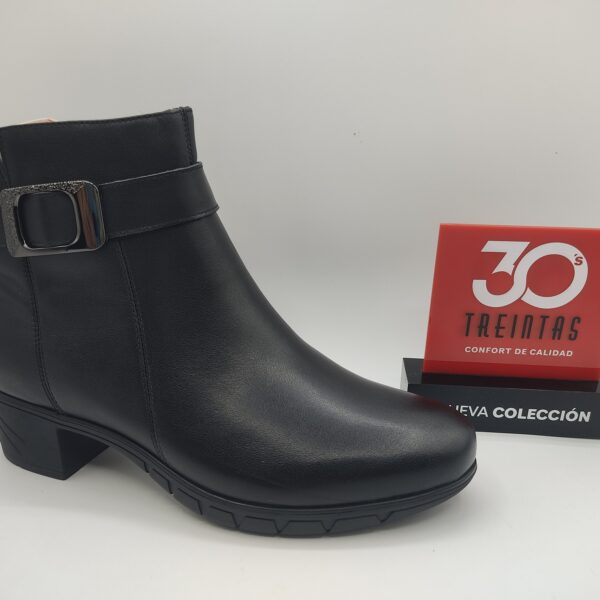 Botín de piel para mujer de la marca Treintas, modelo 4630 en color negro. Suela de goma antideslizante y tacón de goma de 4 cm de alto. Fabricado en piel negra. Detalle de correa con hebilla palteada al tobillo. Cierre con cremallera. #botínpielnegramujer #botíntacónbajomujer #botínnegroconfortable #botíntreintasnegro